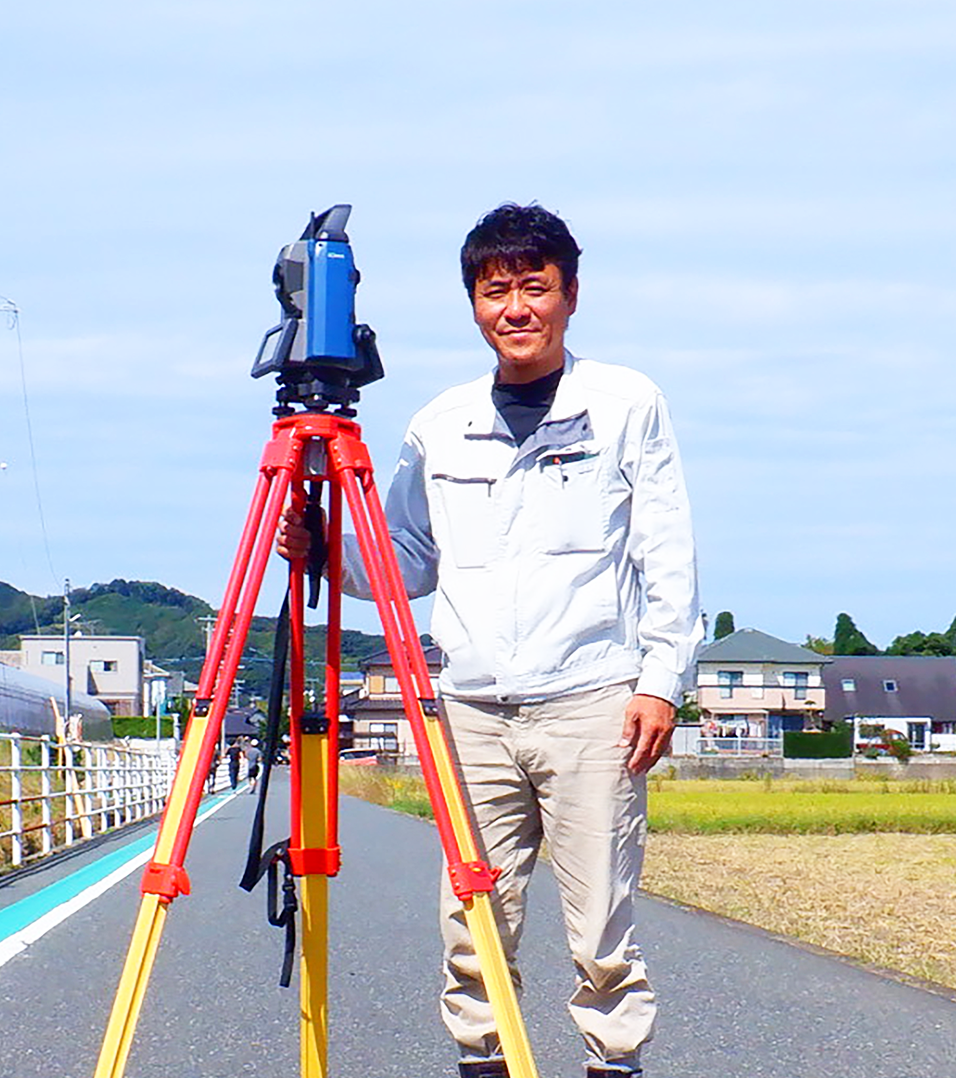 測量機器の前に立つ代表の写真
