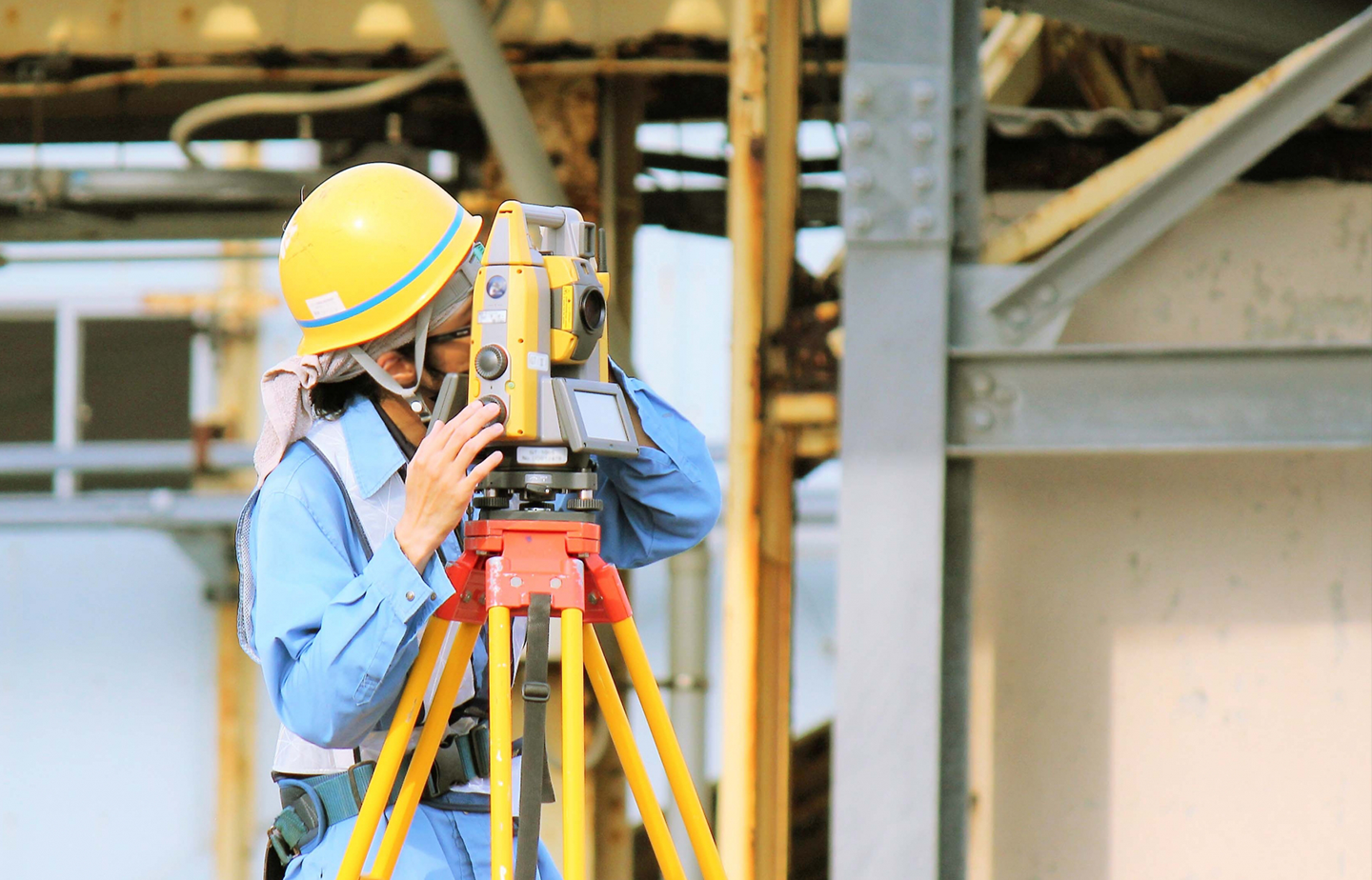 測量機器を操作するヘルメット姿の技術者