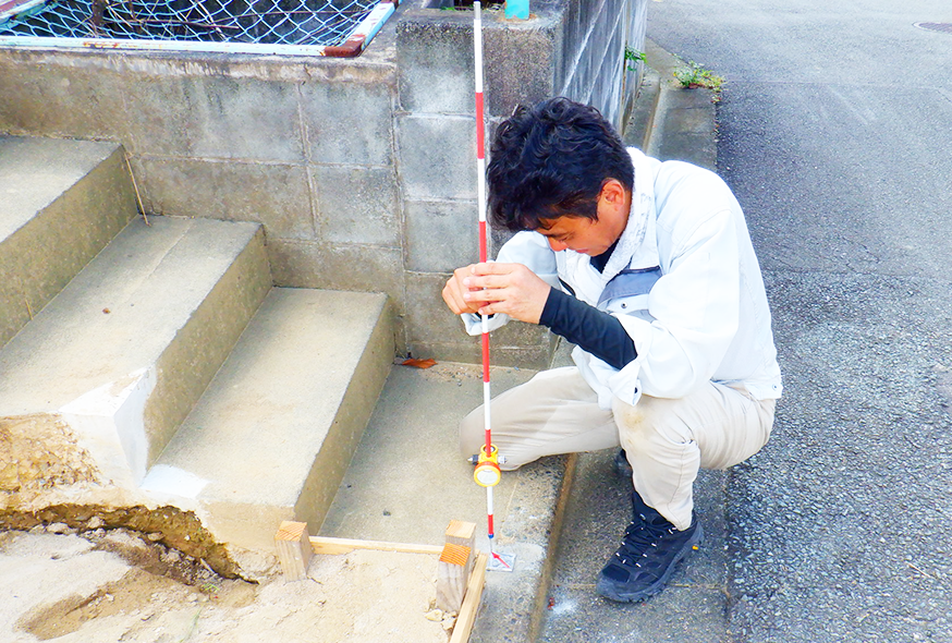 階段の段差を測量する技術者