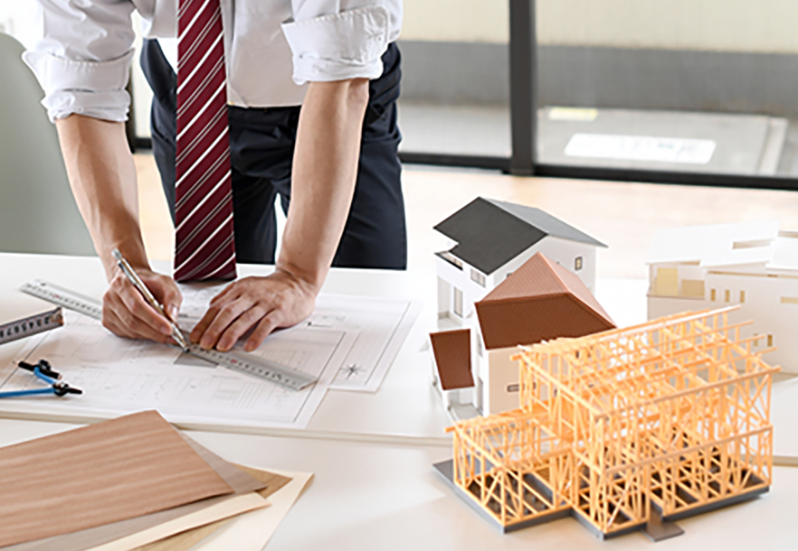 建築図面と模型を前に打ち合わせをする人々